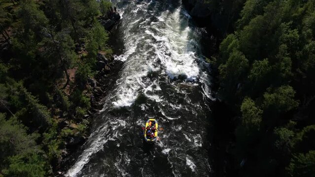 the drone flies over a stormy mountain river that flows in the middle of a dense taiga forest rafting team rafts on the waves tossing the boat 4k high quality footage Umba Kola peninsula waterfall 