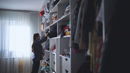 The mother is a housewife looking for clothes in the closet.
