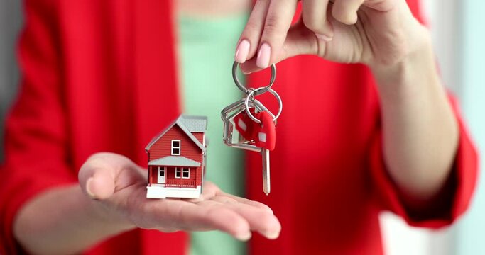 Key and house model in hands of female manager. Real estate purchase and sale and loan and mortgage concept