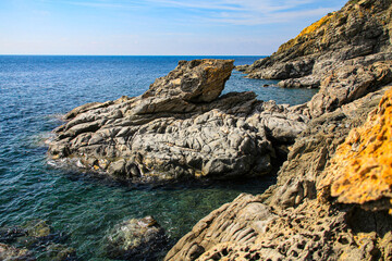 Fototapeta na wymiar Stony rocky shore of the sea, on a sunny summer day. A beautiful view of the rocks and the sea of Mount Athos. Greece.