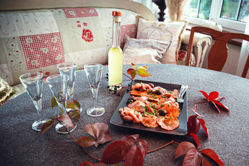 Italian meat plate served with limoncello on sunny table in front of the window