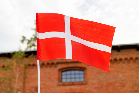 Waving flag of Denmark against the background of a building and sky.