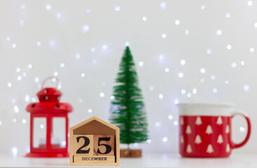 calendar December 25, small Christmas tree, red cup and lantern on festive light background. holidays celebrations.