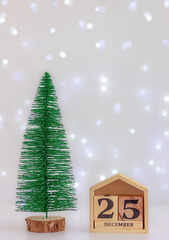 wooden calendar with December 25 and small green fir on festive light. celebration, decorations, winter holiday
