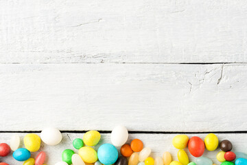 Mixed colourful candies on white wooden background with copyspace