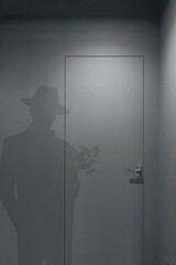 The shadow of a man in a hat who comes to visit with a bouquet of flowers.