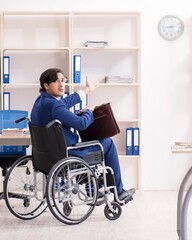 Young male employee in wheelchair working in the office