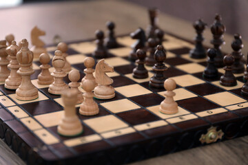 The chess board with the pieces in the dark vintage room interior