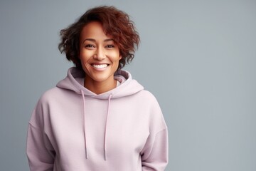 portrait of a african american mid age smiling woman in hoodie on grey background