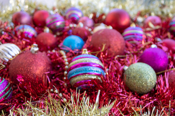 Colorful blurry Christmas balls among shiny tinsel background
