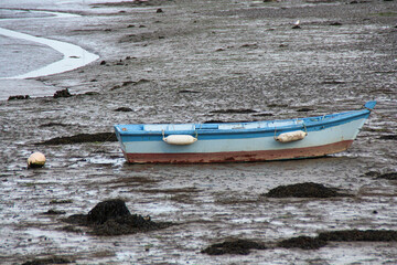 barque bleue et rouge échouée sur la plage à marée basse