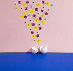Flowers above the eggshells on the dark blue and purple background. Minimal creative concept. Easter pattern. Floral layout. Copy space.