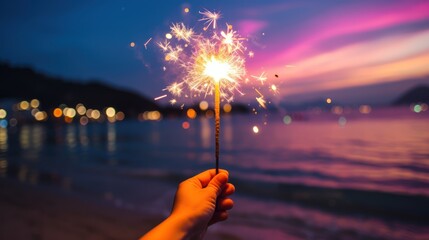 Burning sparkler in hand on the background of the sea.