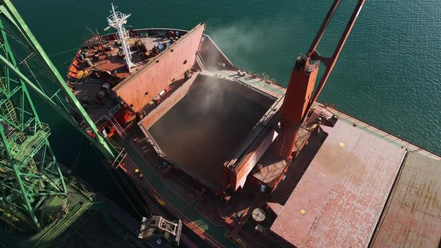 Aerial view of big cargo ship bulk carrier is loaded with grain of wheat in port at sunset