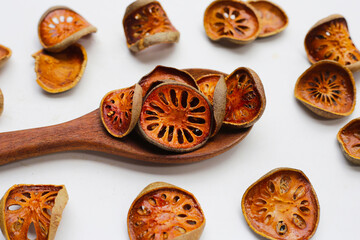 Dried bael fruit slices on white background.