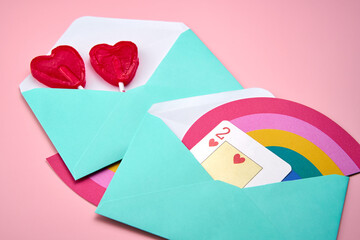 Love letters with rainbow and heart-shaped lollipops on top of a pink background
