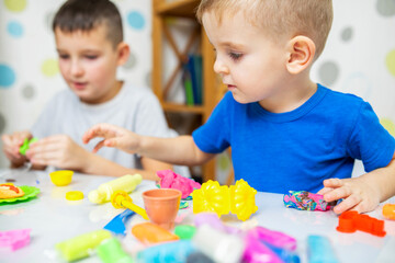 Children enthusiastically play with plasticine, play dough on white table