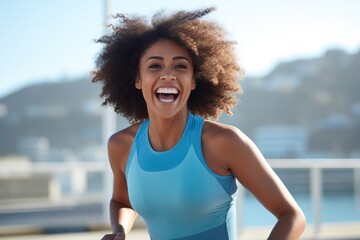 Young afro american woman runner running on city bridge road against blue background - obrazy, fototapety, plakaty
