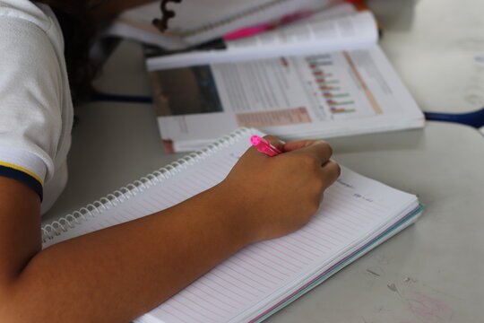 Aluna fazendo atividade do livro em sala de aula. 