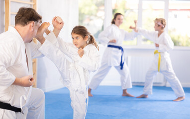 Fototapeta na wymiar Father and daughter karatekas in kimonos practice karate fighting in studio
