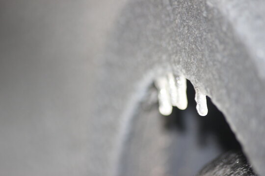 Eisregen mit Eis überzogenes Auto. Graues Auto mit Eisregen bedeckt, Eiszapfen, Schlechtes Fahrwetter im gefrorenen Wasser