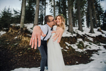 A young couple, the bride and groom, smilingly show off their wedding rings against the background...