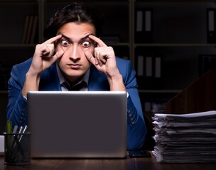 Young male employee working night in the office