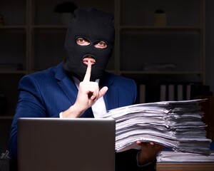 Male employee stealing information in the office night time