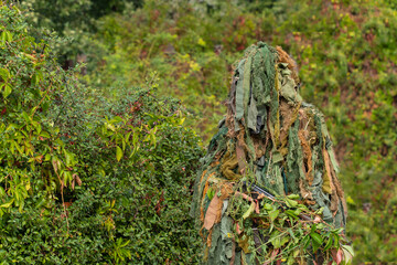 A soldier wearing a military camouflage outfit blending into a green background