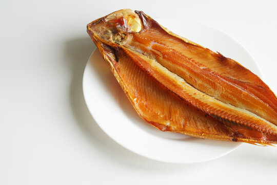 Prepared smoked Baikal omul in a white plate. Innards of gutted smoked fish. A rare fish delicacy is omul. Photo.