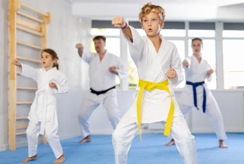 Fototapeten Kata karate teacher conducts classes and performs movements and fighting techniques together with active family students to prepare them for competitions. © JackF