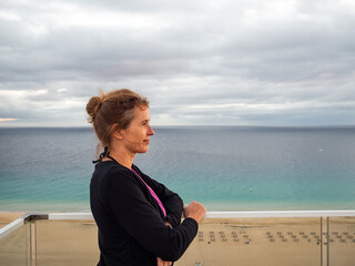 Portrait of a mature woman standing on top of a terrace at the sea