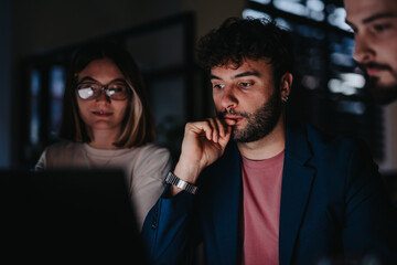 Colleagues working late to meet project deadline, discussing strategies and analyzing data for business growth. Teamwork focused on market research, product development and networking to target group.