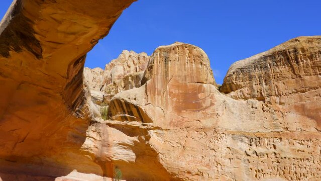 Establishing shot of mountain trail with red rocks background in Hickman Natural Bridge Trail, Capital Reef National Park, Utah, North America. Day time on October 2023. Still camera view. ProRes 422 