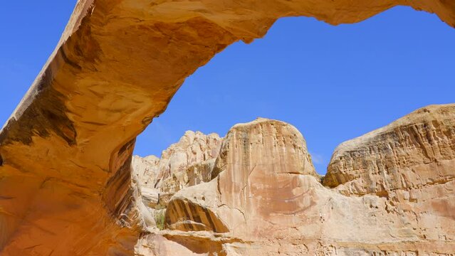 Establishing shot of mountain trail with red rocks background in Hickman Natural Bridge Trail, Capital Reef National Park, Utah, North America. Day time on October 2023. Still camera view. ProRes 422 
