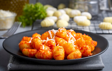 Traditional Italian food potato gnocchi with tomato sauce, parmesan cheese and fresh basil on dark table. Top view. Healthy food.