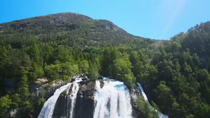 Furebergsfossen waterfall in Norway on a sunny day, aerial footage flying backwards 