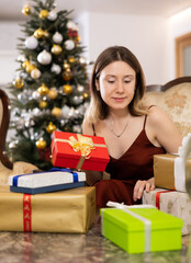 Fototapeta na wymiar Young woman, being in anticipation of the holiday, prepares Christmas presents for guests at home
