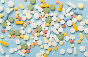 Different medical pills and capsules on wooden background, top view