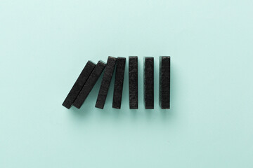 Black domino tiles on color background, top view