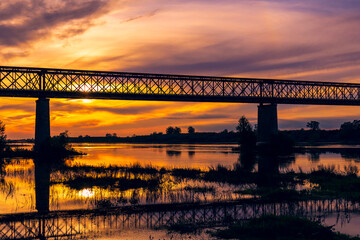 Old steel bridge at sunset. Bridge over the Tagus river, in the portuguese village of Chamusca - Ribatejo - Portugal. Bridge Isidro dos Reis - Chamusca