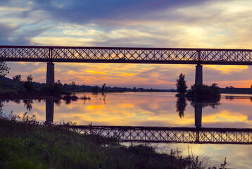 Old steel bridge at sunset. Bridge over the Tagus river, in the portuguese village of Chamusca -...