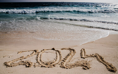 2024 written in white sand on tropical beach, happy New Year