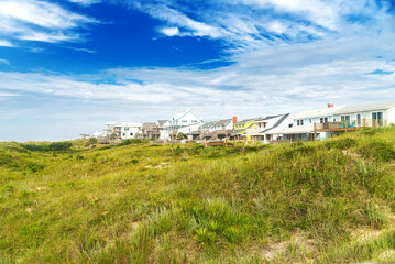 Fototapeta na wymiar Rows of houses on the shores of the Atlantic Ocean. Tall grass and blue sky.
