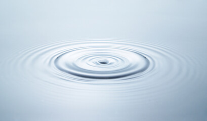 Blue water circles surface with rings and ripples from drop