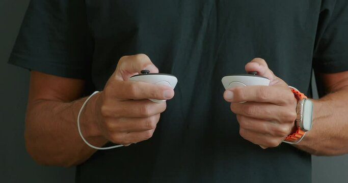 Close-up of hands holding white controllers, plays in virtual reality.