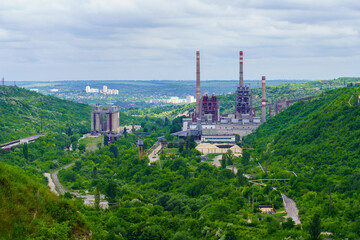 Fototapeta premium Plant or factory. Industrial area in a picturesque beautiful green area. Background with selective focus and copy space