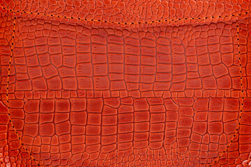 Background is made of red crocodile skin. Leather bag close-up.