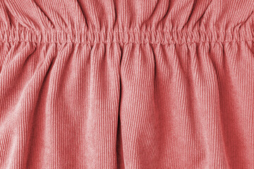 Red corduroy fabric gathered with elastic close-up. Velveteen texture with folds and drapery. Cloth...