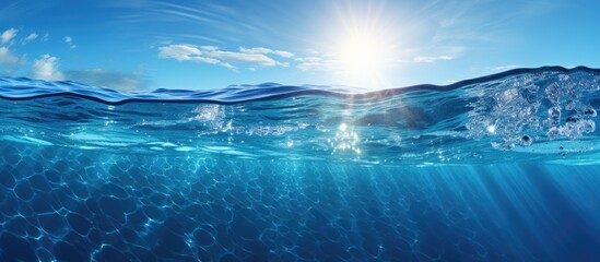 Fototapeta premium As the sun's radiant light illuminates the clear, deep blue waters of the ocean, a mesmerizing abstract world unfolds before their eyes; the rippling texture of the sea creates a cool and refreshing